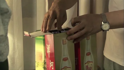 The man opens the packaging of white liquor and finds coins inside Stock Footage 276451135