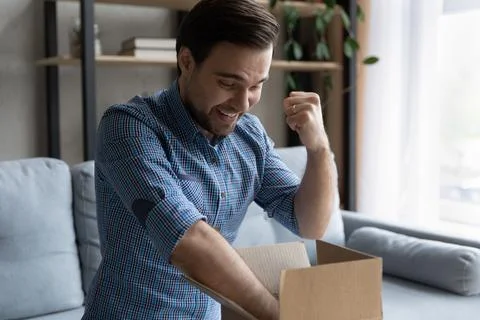 Man opens parcel box with long-awaited goods feels overjoyed 스톡 사진