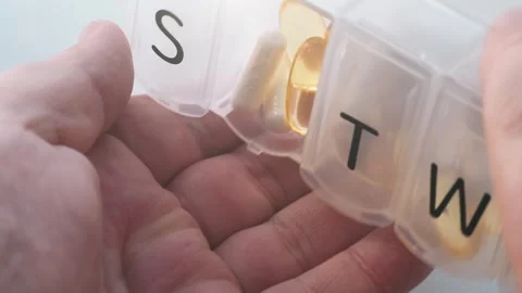 Man opens pill organizer and pours daily dose of dietary supplements Video stock 250239591