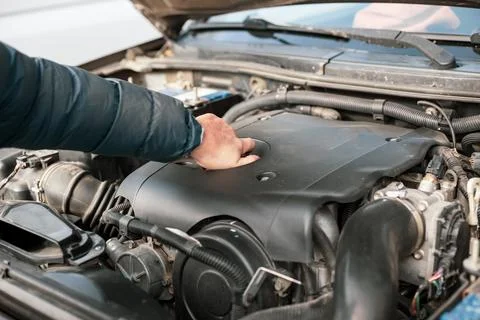 A man opens the plug on a car engine to replace and top up oil, and maintai.. Foto stock