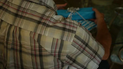 Man opens present from behind angle over glass table Stock Footage 210873387