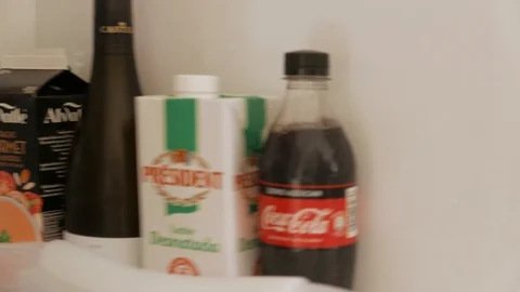 A man opens a refrigerator and grabs a bottle of Coke Stock Footage 124859899