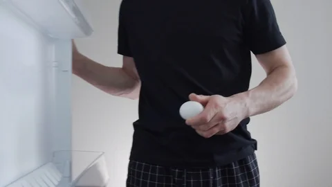 Man opens the refrigerator and takes out a couple of chicken eggs Stock Footage 121314491
