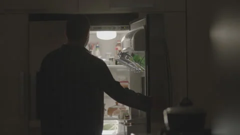 A man opens a refrigerator in a dimly lit kitchen Stock Footage 336236817