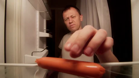 A man opens the refrigerator at night on the shelf is a spoiled sausage Stock Footage 144934645