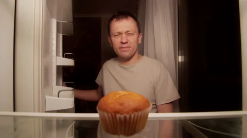 Man opens the refrigerator at night on the shelf is one cupcake, a disgruntled Stock Footage 145123311