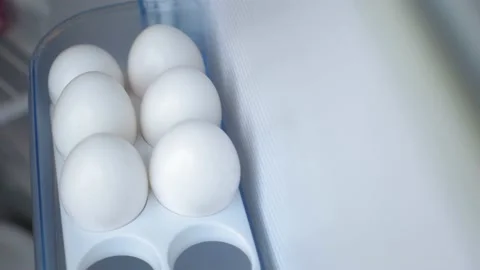 A man opens the refrigerator, there on the shelf are chicken eggs in a white Stock Footage 201736003