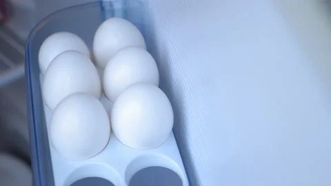 A man opens the refrigerator, there on the shelf are chicken eggs Video stock 202050376