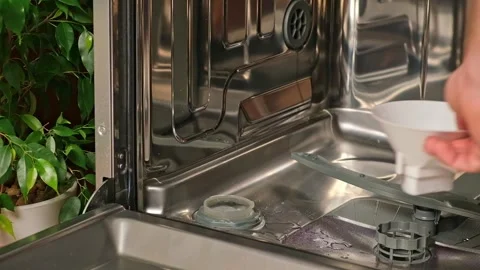 Man opens salt compartment of dishwasher, pours salt into through funnel Stock Footage 244638039