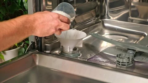 Man opens salt compartment of dishwasher, pours salt into through funnel Stock Footage 244638074
