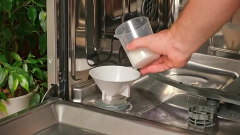 Man opens salt compartment of dishwasher, pours salt into through funnel Stock Footage 244804508