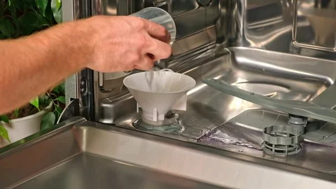 Man opens salt compartment of dishwasher, pours salt into through funnel Stock Footage 245657768