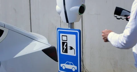 Man opens the socket of his electric white car to connect the recharge plug. Alt Stock Footage 128945839