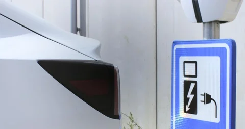 Man opens the socket of his electric white car to connect the recharge plug. Alt Stock Footage 128945910