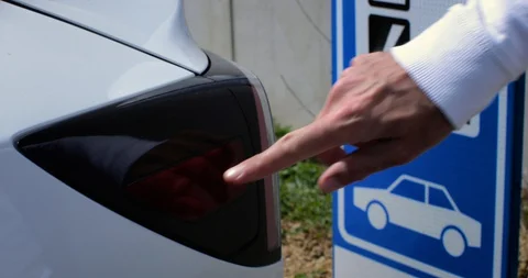 Man opens the socket of his electric white car to connect the recharge plug. Alt Stock Footage 128945912