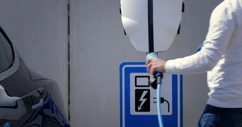 Man opens the socket of his electric black car to connect the recharge plug. Alt Stock Footage 128946235