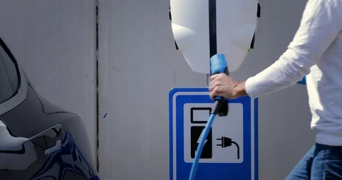 Man opens the socket of his electric black car to connect the recharge plug. Alt Stock Footage 128946333