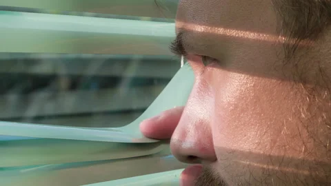 A man opens sun blinds of the window by his hand and he looks outside 스톡 동영상 97687011