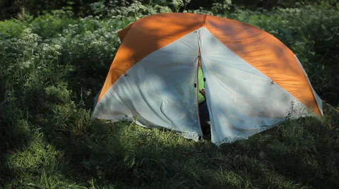 The man opens the tent and starts to talk on the phone in the forest Stock Footage 64309923