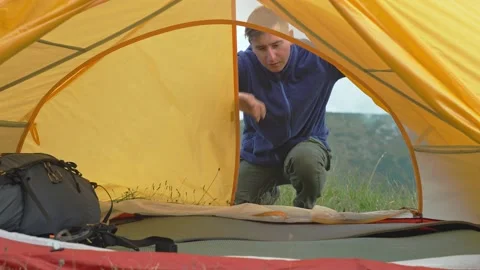 The man opens the tent and takes out a backpack. Hiking in nature, tourism Stock Footage 236018018