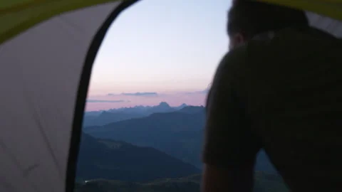A man opens the tent from the inside. Mountain view at sunrise Stock Footage 266419087