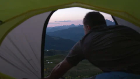 A man opens the tent from the inside. Mountain view at sunrise Stock Footage 266419090