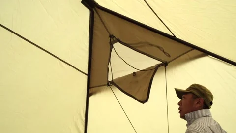 A man opens a triangular window in the roof of the tent inside Stock Footage 247049059