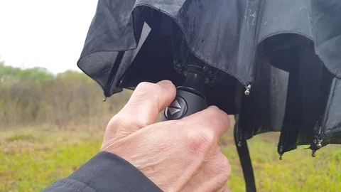 A man opens an umbrella slow motion. Click on the umbrella button to open it. Stock Footage 107816458
