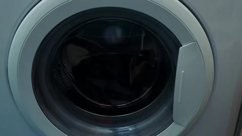 A man opens a washing machine door and puts in dirty clothes - closeup Stock Footage 79436173