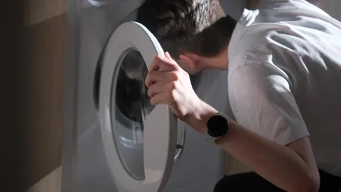 A man opens the washing machine door and smells an unpleasant odor Stock Footage 277942938