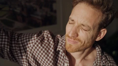 Man opens window and shields eyes from bright sunlight, squinting and raising Stock Footage 314891976