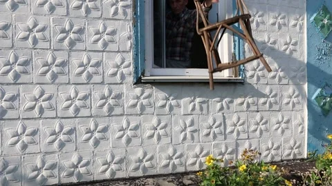 The man opens the window and throws out the old chair Stock Footage 142060996