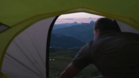 A man opens the zipper of the  tent from the inside. Mountain view at sunrise Stock Footage 266419132