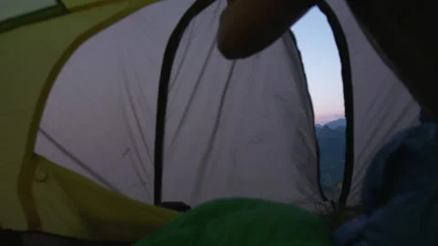A man opens the zipper of the  tent from the inside. Mountain view at sunrise Stock Footage 266420292