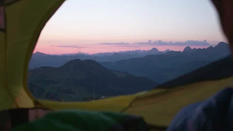 A man opens the zipper of the  tent from the inside. Mountain view at sunrise Stock Footage 266420774