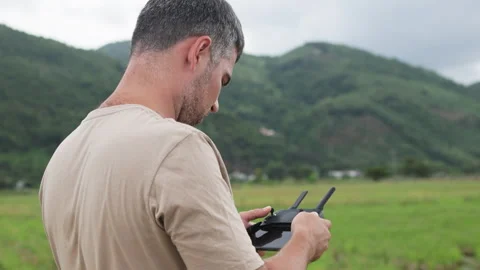 A man operates a drone against a backdrop of green hills. Stock Footage 321727841