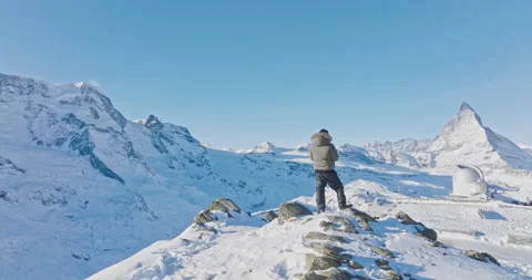 Man operates drone remote control with Matterhorn sunset background. Swiss alps. Video stock 229764331