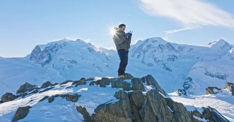Man operates drone remote control with Matterhorn sunset background. Swiss .. Stock Photos