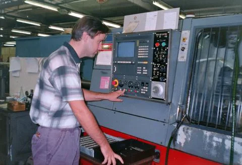 A man operates a numerical control machine in a factory, archive photo, 90s. Stock Photos