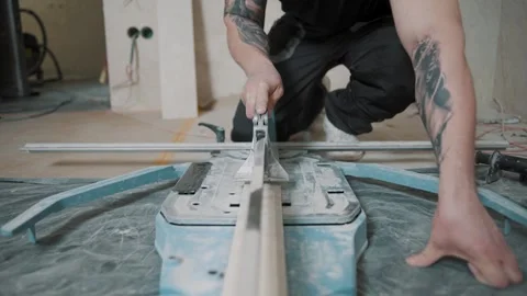 Man operates slow motion tile cutter for precise detailing in home Stock Footage 307039939