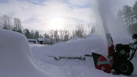 A man operates a snow blower, pushing through thick snow in a winter landsc.. Stock Footage 287073846