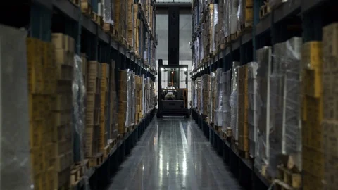 Man operating and driving machinery in warehouse aisle by stock. 動画素材 88027465