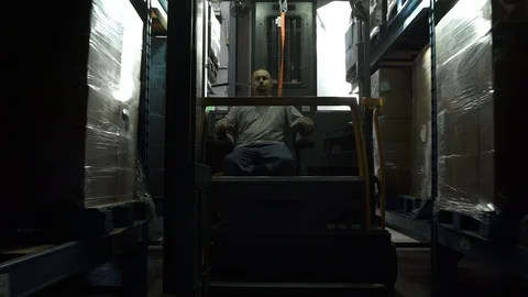 Man operating and elevating forklift truck in warehouse. 動画素材 88105015