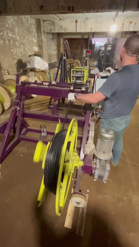 Man operating a cable winding machine. Worker manufacturing electrical cable. Stock Footage 322002904