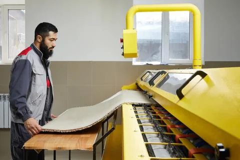 Man operating carpet automatic washing machine in professional laundry service Stock Photos