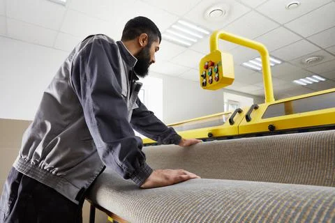Man operating carpet automatic washing machine in professional laundry service Stock Photos