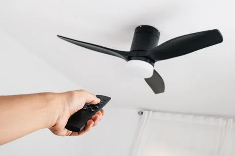 Man operating a ceiling fan with remote control Stock Photos