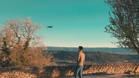 Man operating a drone with remote control in front of a beautiful landscape Stock Footage 104814989