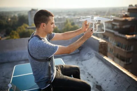 Man operating a drone with remote control on rooftop Stock Photos