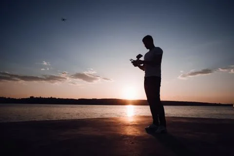 Man operating a drone with remote control. Dark silhouette Stock Photos